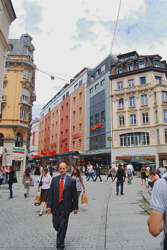 8 - A pedestrian street view in Lausanne, Switzerland, featuring a McDonald's and a Coop City department store along Rue Saint-Laurent